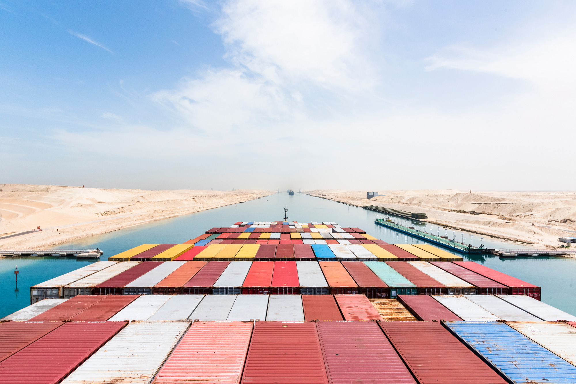 Containerschiff mit Frachtcontainern im Suezkanal in Ägypten als zentrale Handelsroute für globale Lieferketten, Blick vom Brückendeck nach vorne
